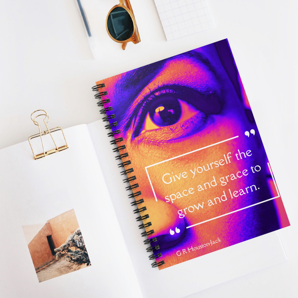Space and grace spiral notebook designed by Gwendolyn R. Houston-Jack laying on a white desk